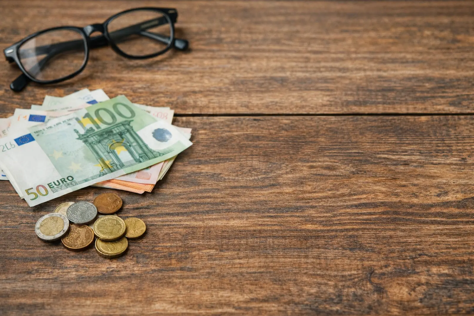 Euro-Banknoten und Notizbuch auf Holztisch als Symbol für finanzielle Bildung und bewusstes Gelddenken